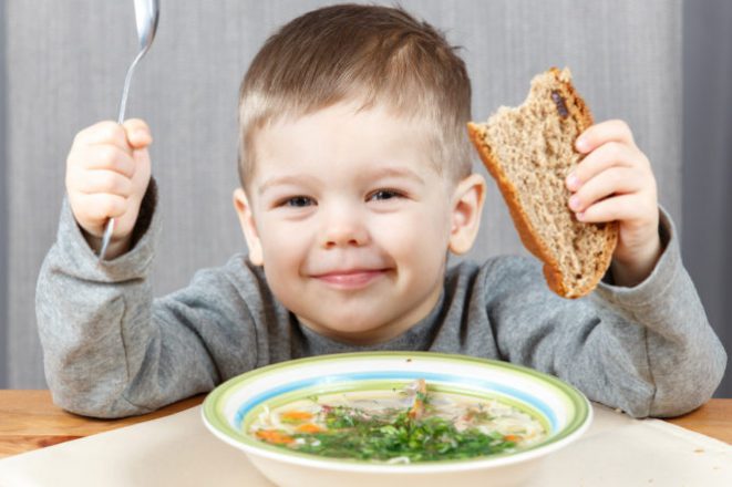 Smiling boy with plate of soup for dinner